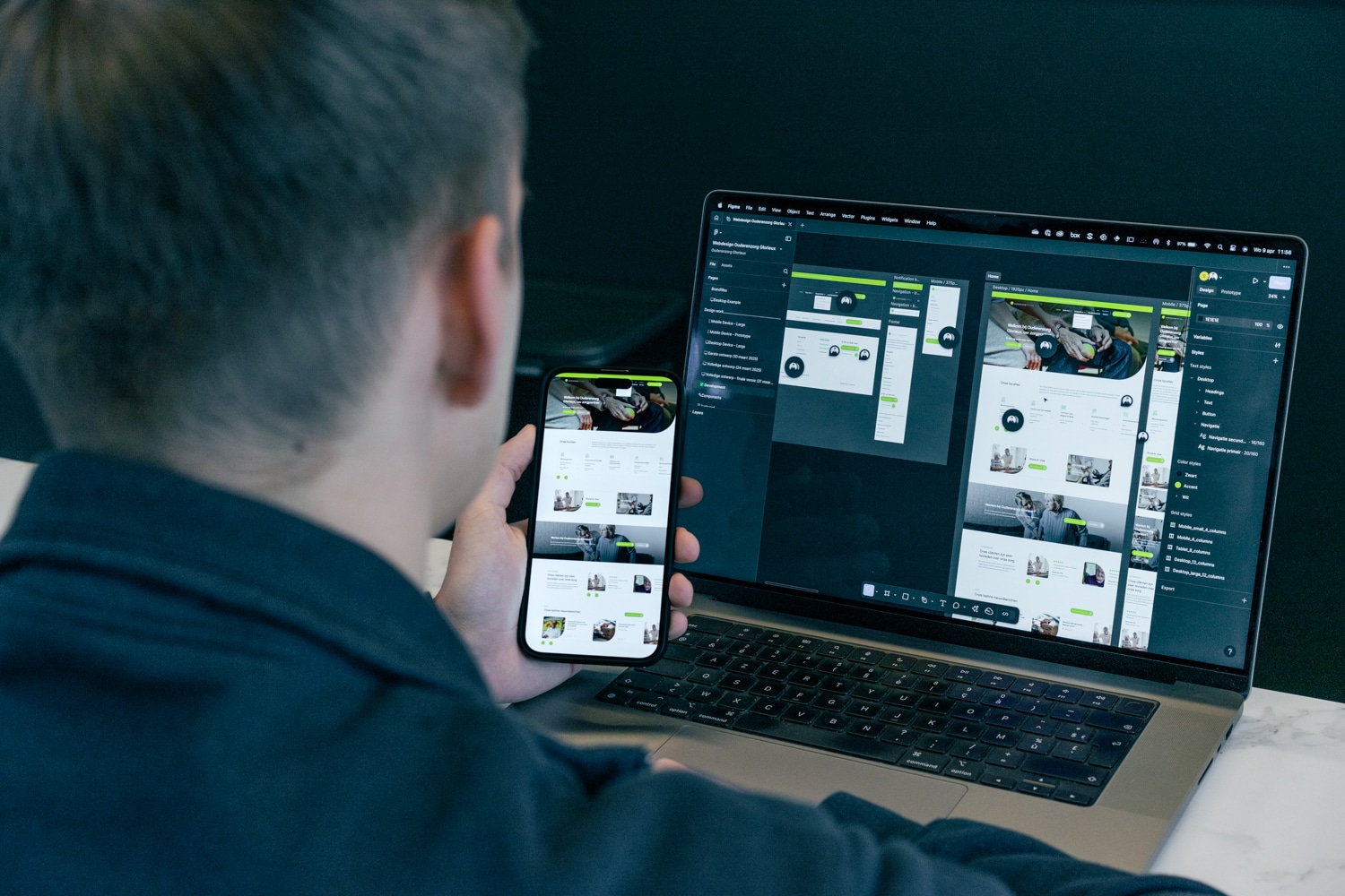 Webdesigner bekijkt een meertalige website op smartphone en laptop tijdens het ontwerp- en ontwikkelproces
